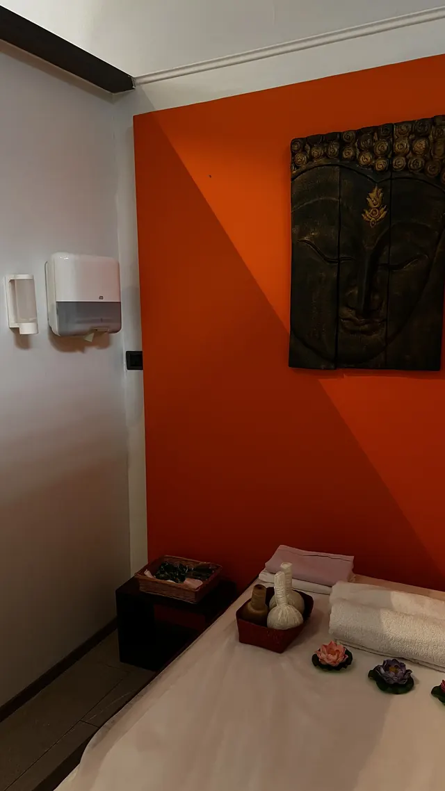 Massage room with an orange wall and a Thai painting